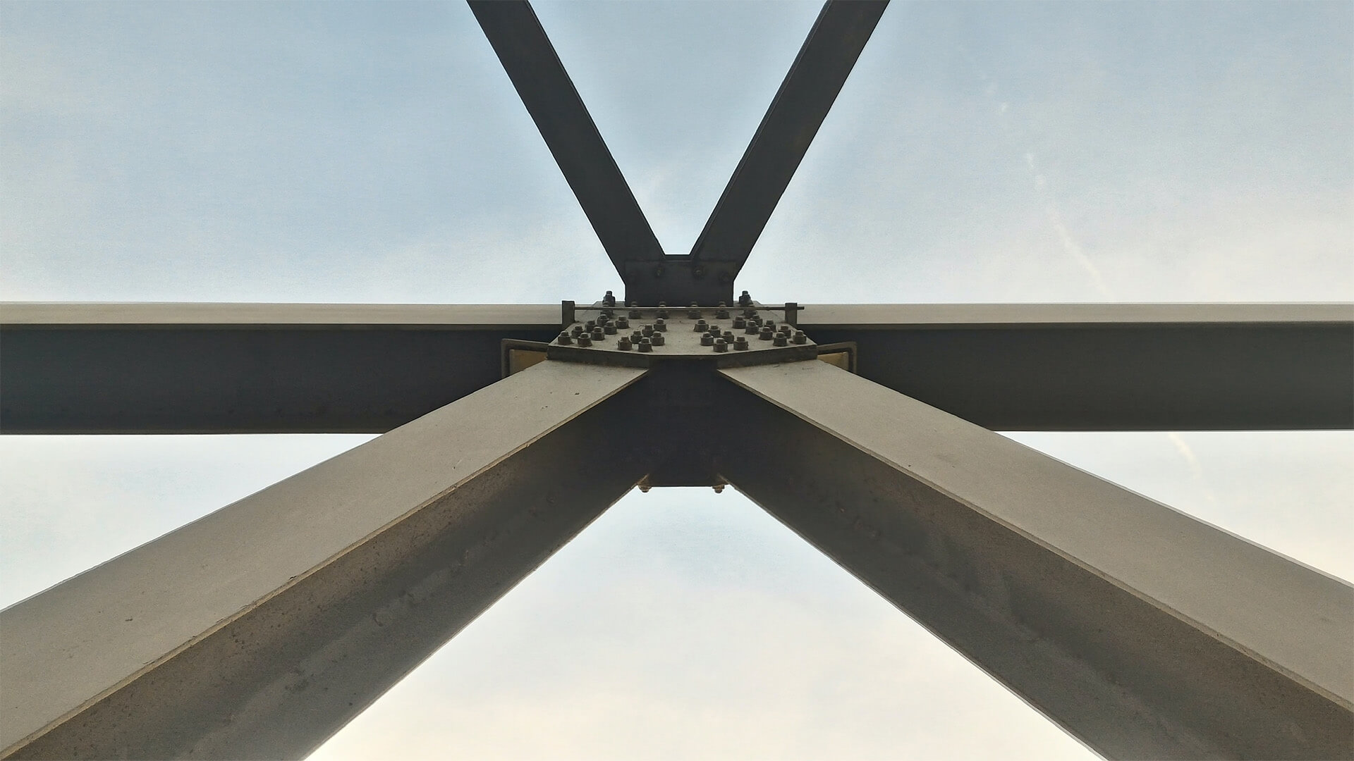 An image of several large iron beams converging outside. A visual metaphor for the topic of this article, Lawyers and project managers